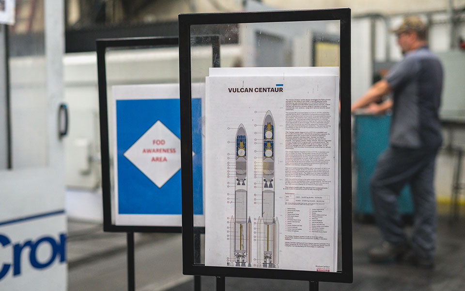 A Vulcan Centaur instruction guide sits in a metal frame in the workshop.