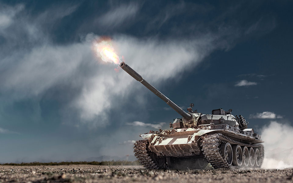 A military tank firing in a field.