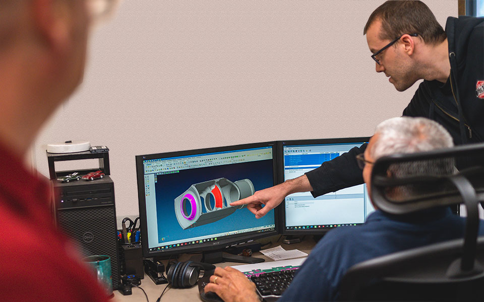 An employee points at a computer screen in front of another employee