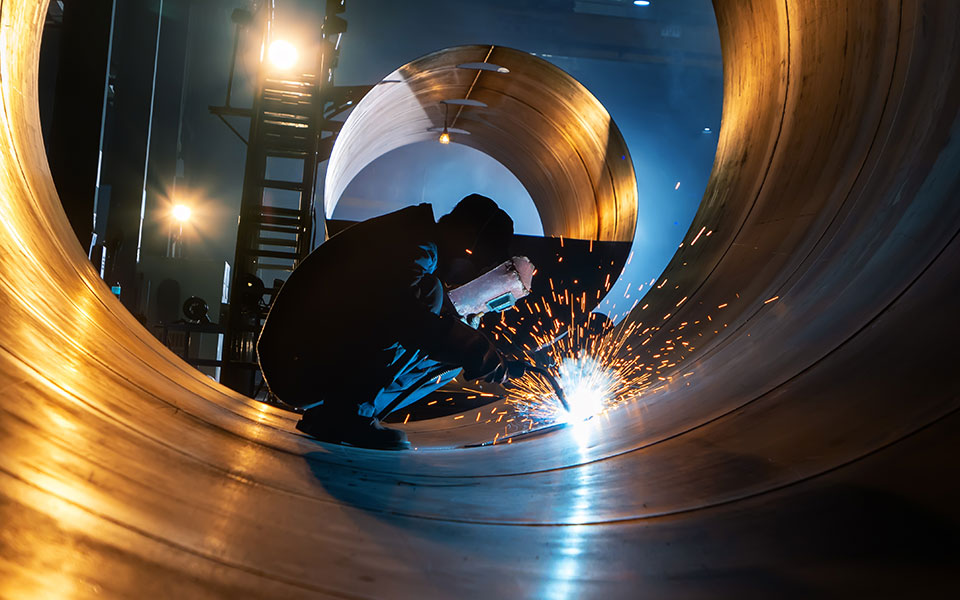 Man welds inside a large metal tube.